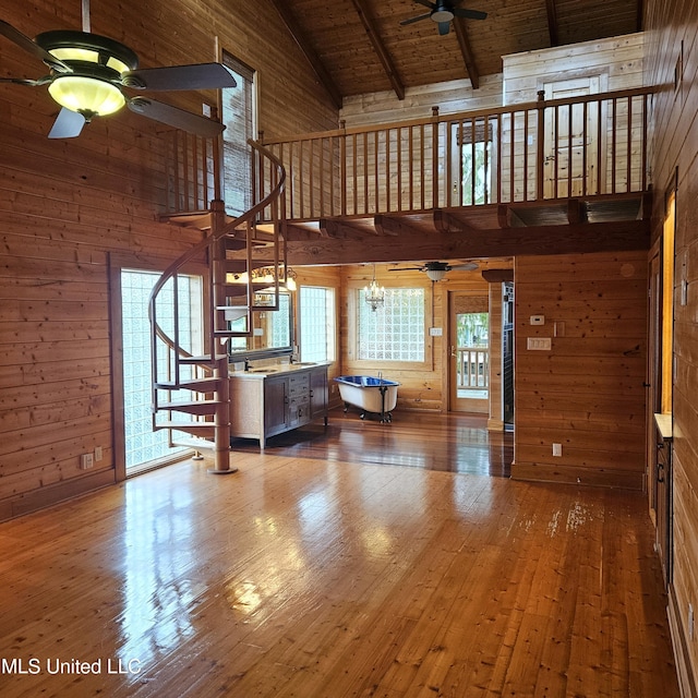 unfurnished living room featuring beam ceiling, wooden ceiling, high vaulted ceiling, hardwood / wood-style floors, and wooden walls