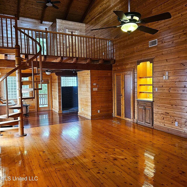 unfurnished living room with hardwood / wood-style flooring, wood walls, wooden ceiling, and high vaulted ceiling