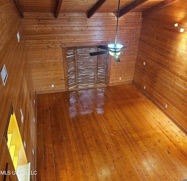 unfurnished living room with vaulted ceiling with beams, wood walls, wood ceiling, and hardwood / wood-style flooring