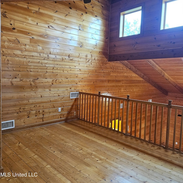 additional living space with hardwood / wood-style floors, lofted ceiling with beams, wood ceiling, and wood walls