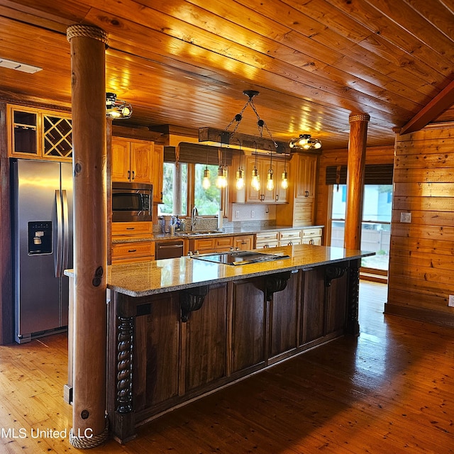 kitchen with a center island, light wood-type flooring, decorative light fixtures, a kitchen bar, and stainless steel appliances