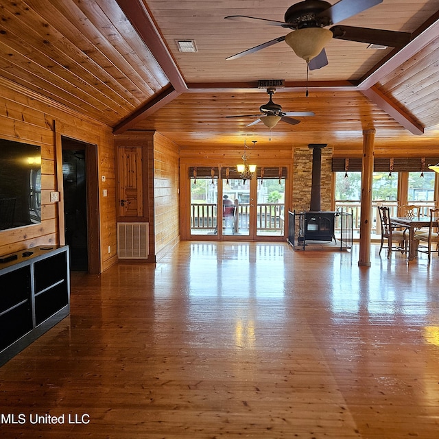 unfurnished living room featuring lofted ceiling with beams, wood-type flooring, a wood stove, and wood ceiling