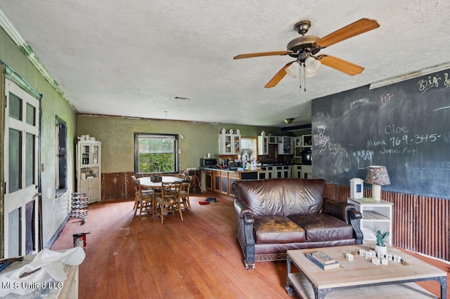 9 Gail St, Hattiesburg, MS 39402 - living room featuring a textured ceiling, wood finished floors, a ceiling fan, a wainscoted wall, and wood walls