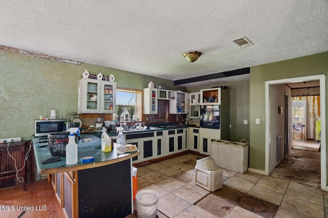 9 Gail St, Hattiesburg, MS 39402 - kitchen featuring oven, a textured ceiling, glass insert cabinets, and gas cooktop