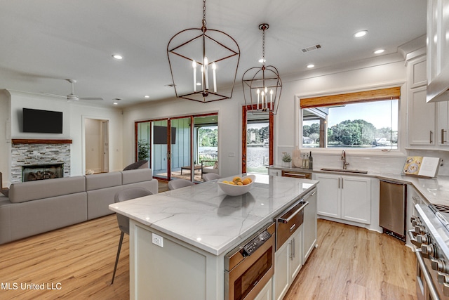 kitchen with a kitchen island, plenty of natural light, hanging light fixtures, white cabinetry, and high end stainless steel range