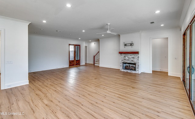 unfurnished living room featuring ceiling fan, crown molding, light wood-type flooring, and a fireplace