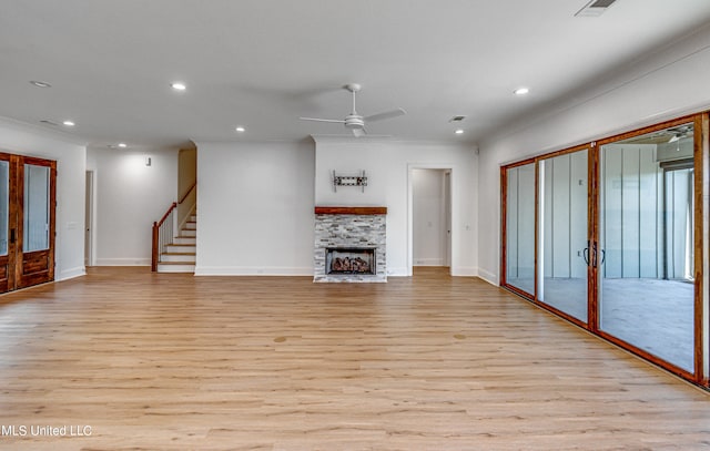 unfurnished living room featuring light hardwood / wood-style flooring, crown molding, a fireplace, and ceiling fan