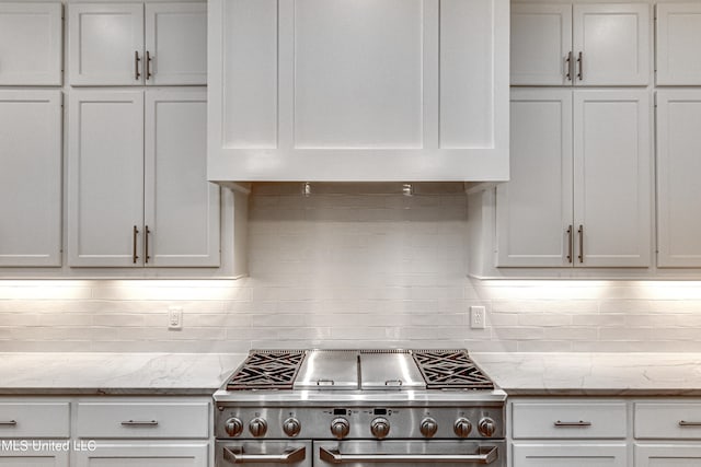 kitchen featuring decorative backsplash, white cabinets, stainless steel range oven, and light stone counters