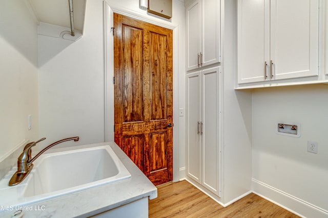 washroom featuring sink, hookup for a washing machine, light hardwood / wood-style floors, and cabinets