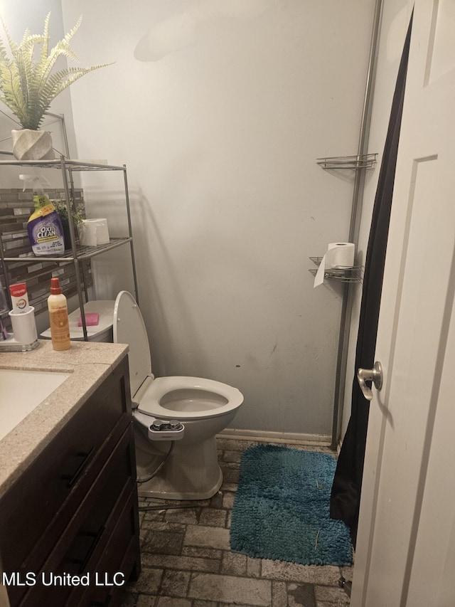 bathroom with toilet, vanity, and baseboards