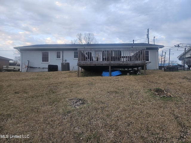 rear view of house with a yard, brick siding, central AC, and a wooden deck