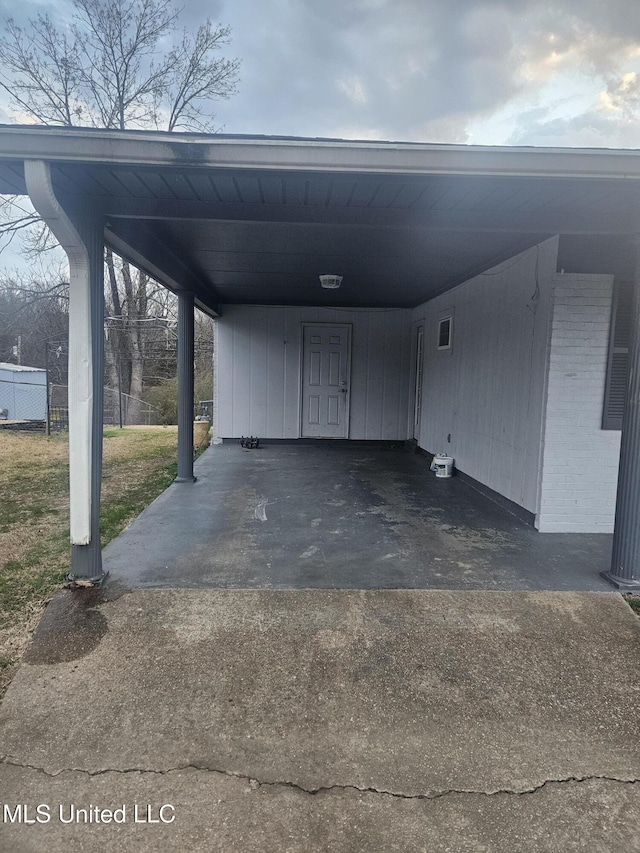 view of car parking with an attached carport, fence, and driveway