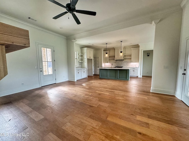 unfurnished living room with ceiling fan, sink, ornamental molding, and hardwood / wood-style flooring