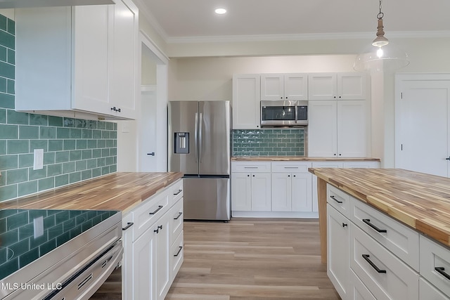 kitchen featuring white cabinets, appliances with stainless steel finishes, hanging light fixtures, crown molding, and wooden counters