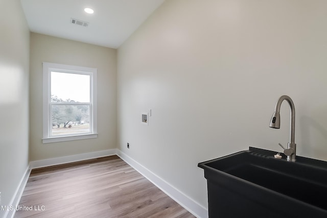 clothes washing area featuring visible vents, light wood-style flooring, a sink, laundry area, and baseboards