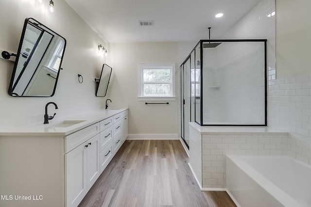 bathroom featuring a shower stall, visible vents, a sink, and wood finished floors