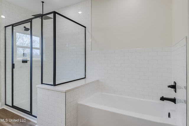 bathroom with a garden tub, wood finished floors, and a stall shower