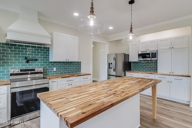 kitchen with stainless steel appliances, premium range hood, butcher block countertops, and white cabinets