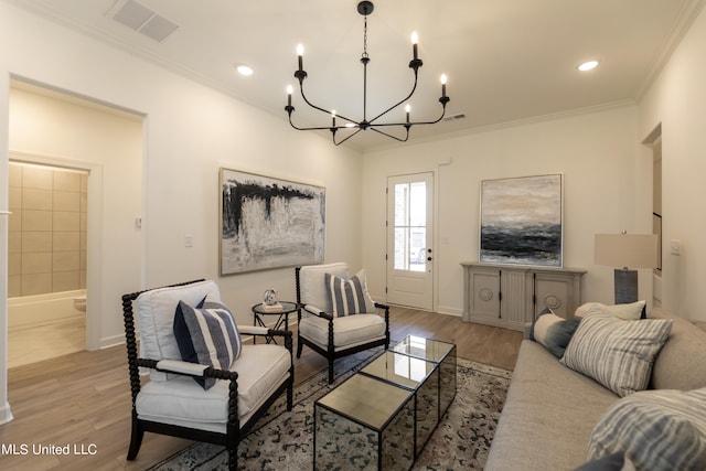 living room with light hardwood / wood-style floors, an inviting chandelier, and ornamental molding