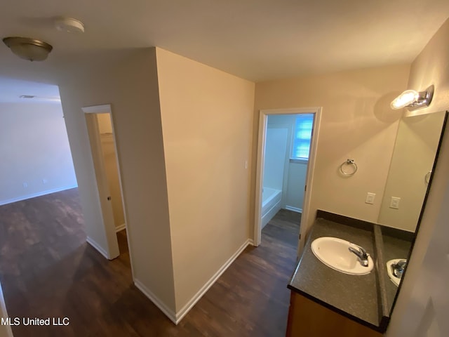 bathroom with vanity, a tub, and wood-type flooring