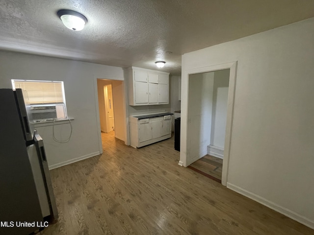 3701 14th St, Gulfport, MS 39501 - kitchen with freestanding refrigerator, a textured ceiling, white cabinetry, wood finished floors, and baseboards