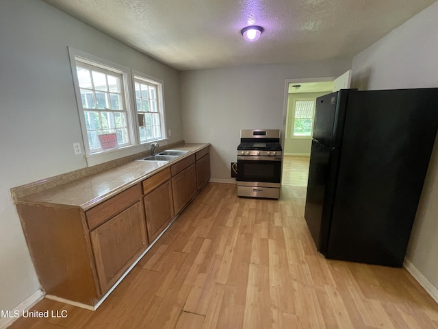 3701 14th St, Gulfport, MS 39501 - kitchen featuring stainless steel gas range, freestanding refrigerator, a sink, light wood-type flooring, and a textured ceiling