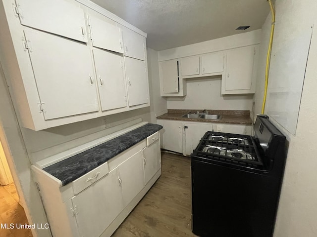 3701 14th St, Gulfport, MS 39501 - kitchen with gas stove, wood finished floors, a sink, and white cabinets
