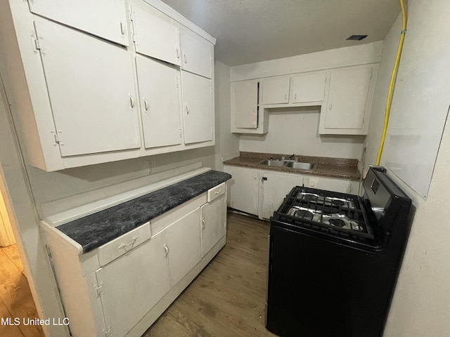 3701 14th St, Gulfport, MS 39501 - kitchen featuring black gas range oven, a sink, white cabinetry, and wood finished floors