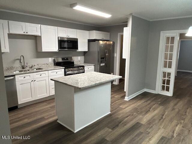 805 Choctaw Dr, Laurel, MS 39440 - kitchen featuring appliances with stainless steel finishes, a sink, ornamental molding, white cabinets, and light stone countertops