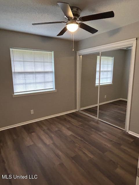 805 Choctaw Dr, Laurel, MS 39440 - unfurnished bedroom with dark wood-style floors, a closet, baseboards, and ceiling fan