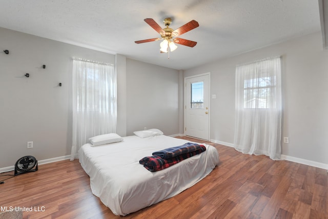 bedroom with multiple windows, ceiling fan, wood-type flooring, and a textured ceiling