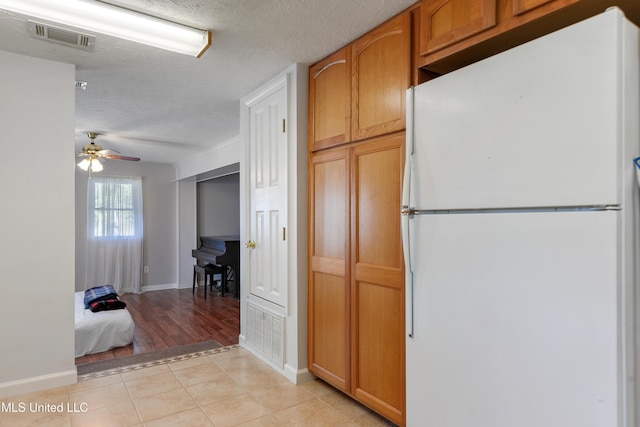 kitchen featuring ceiling fan, white refrigerator, light tile patterned floors, and a textured ceiling