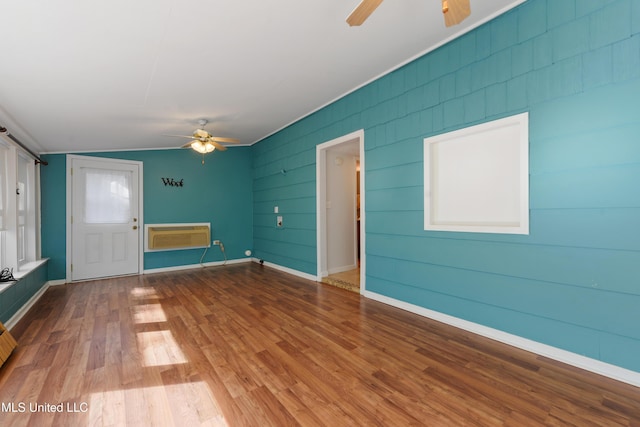 interior space featuring wood-type flooring, vaulted ceiling, a wall mounted AC, and ceiling fan