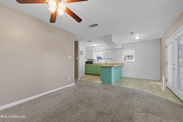 unfurnished living room with ceiling fan, sink, and light colored carpet