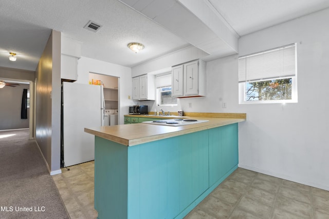 kitchen with a wealth of natural light, kitchen peninsula, white appliances, white cabinets, and washer and dryer