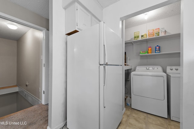 clothes washing area with washing machine and dryer and a textured ceiling