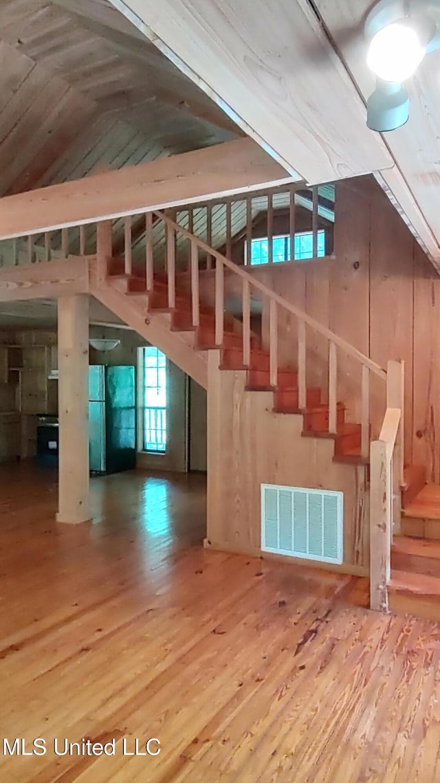 stairs featuring lofted ceiling, wood finished floors, and visible vents