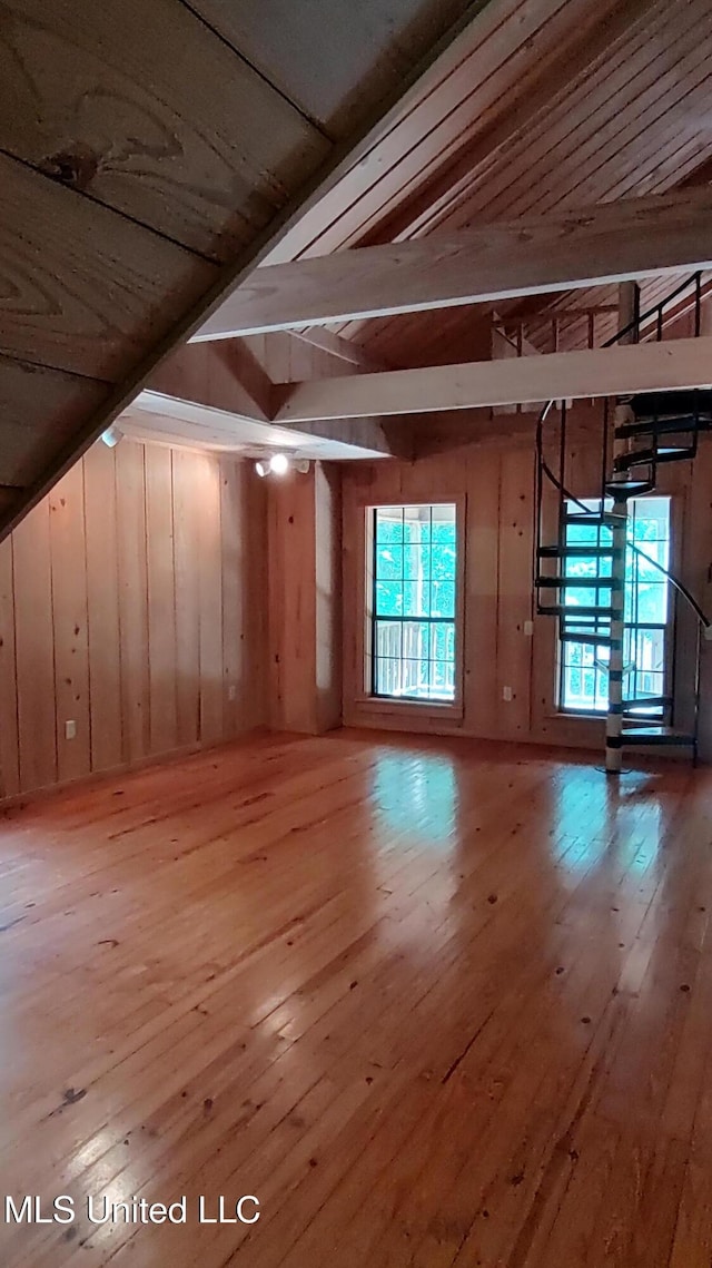 bonus room featuring hardwood / wood-style floors, wood walls, and a healthy amount of sunlight