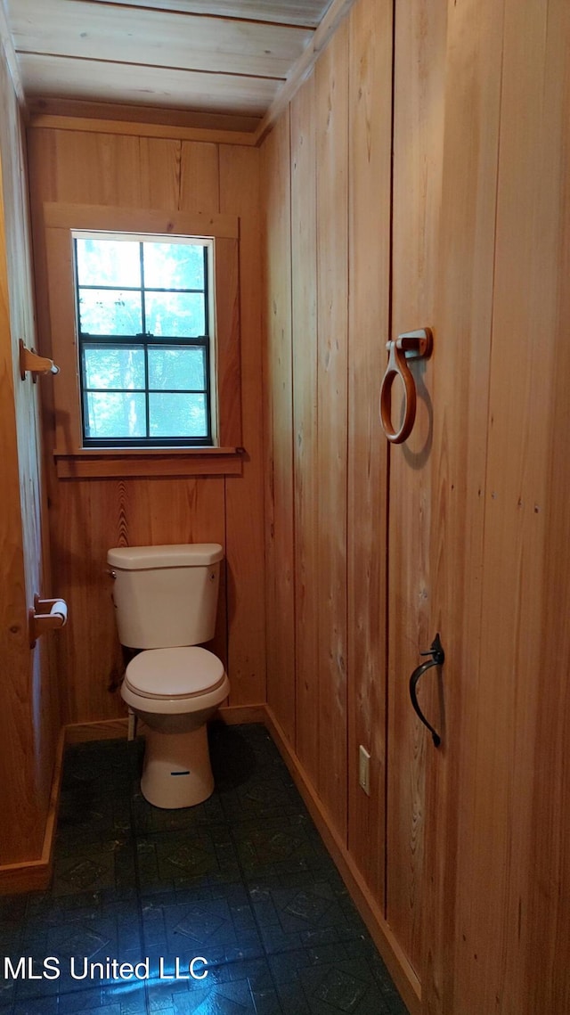 bathroom featuring wood walls and toilet