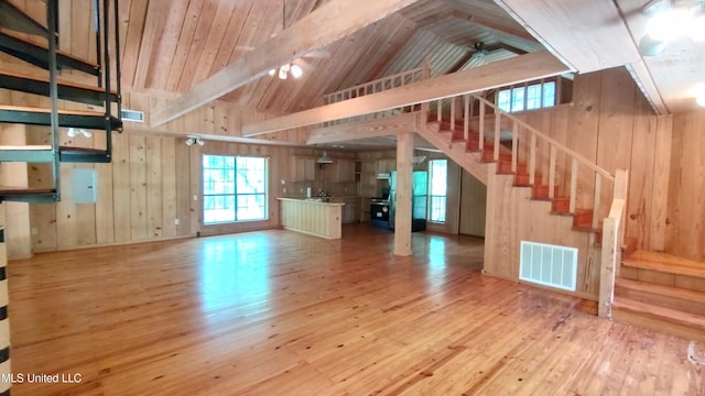 unfurnished living room with stairway, wood-type flooring, lofted ceiling, and visible vents
