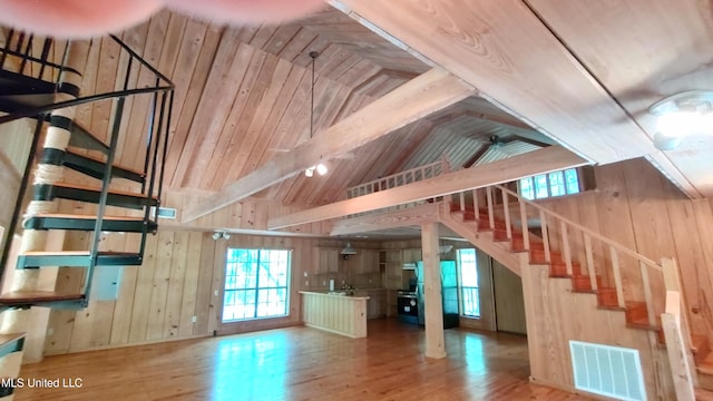 unfurnished living room featuring wood finished floors, stairs, visible vents, and plenty of natural light