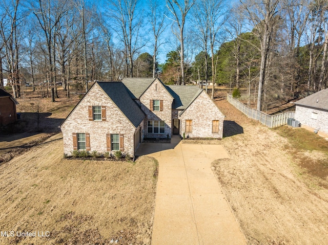 view of front of home featuring stone siding, a shingled roof, fence, and concrete driveway