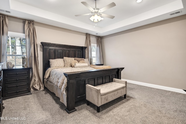 carpeted bedroom featuring a ceiling fan, a raised ceiling, visible vents, and baseboards