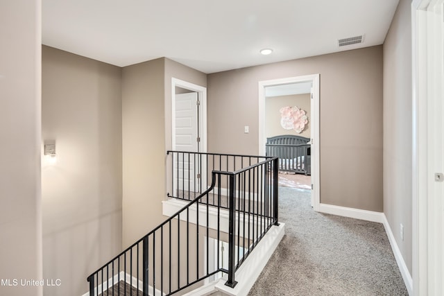 hallway featuring visible vents, carpet, an upstairs landing, and baseboards