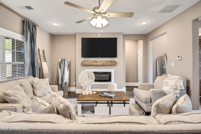 living room with visible vents, wood finished floors, and a glass covered fireplace