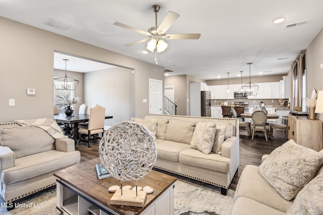 living room featuring ceiling fan with notable chandelier, recessed lighting, visible vents, and wood finished floors