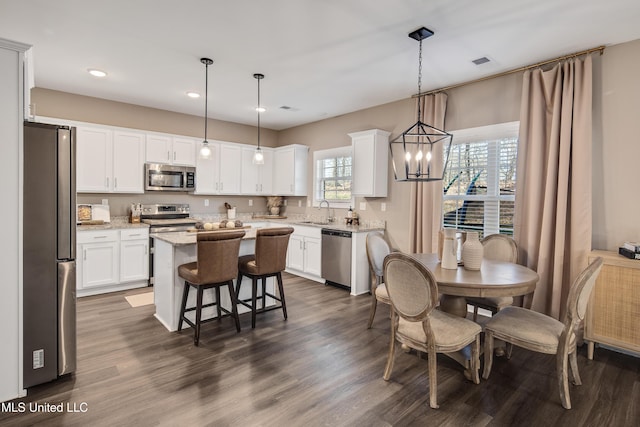 kitchen featuring stainless steel appliances, a kitchen island, visible vents, and white cabinetry