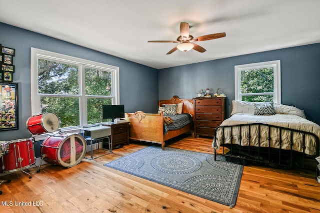 bedroom with ceiling fan, multiple windows, and light wood-type flooring