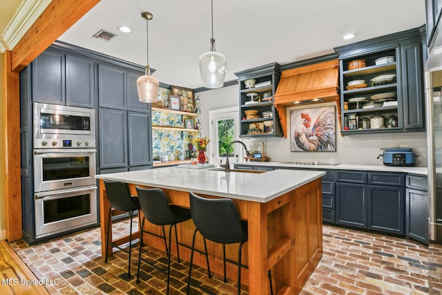 kitchen featuring appliances with stainless steel finishes, a breakfast bar, a kitchen island with sink, and pendant lighting