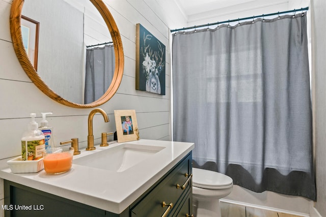 bathroom featuring vanity, toilet, wood-type flooring, and wooden walls